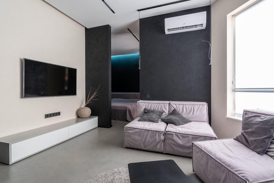 Contemporary living room with sleek furniture, TV, and air conditioning in a modern apartment.